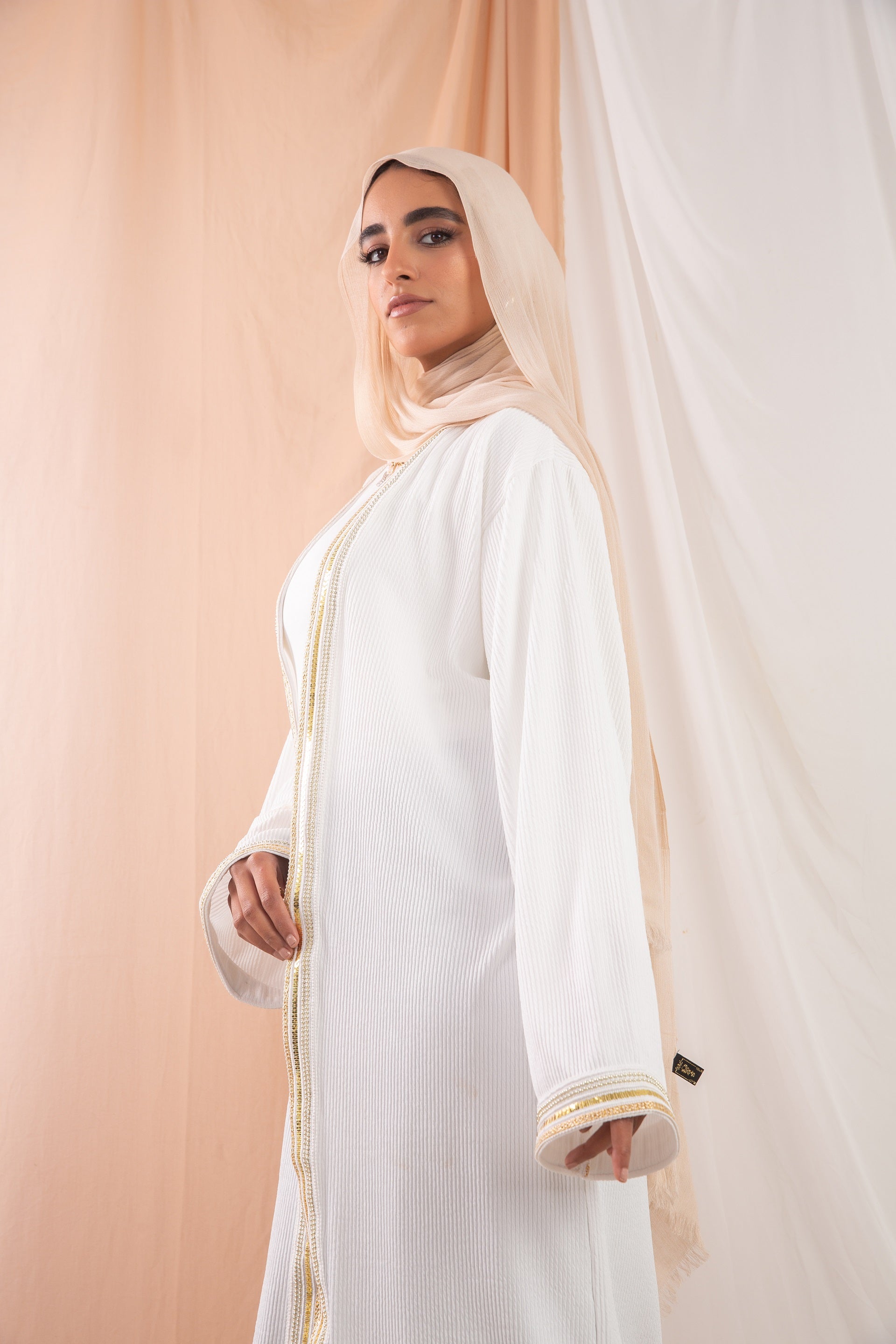 Nojom Kaftan  Off White crafted from crinkle rib-knitted fabric, is adorned with delicate gold lines, adding a touch of elegance and sophistication.
