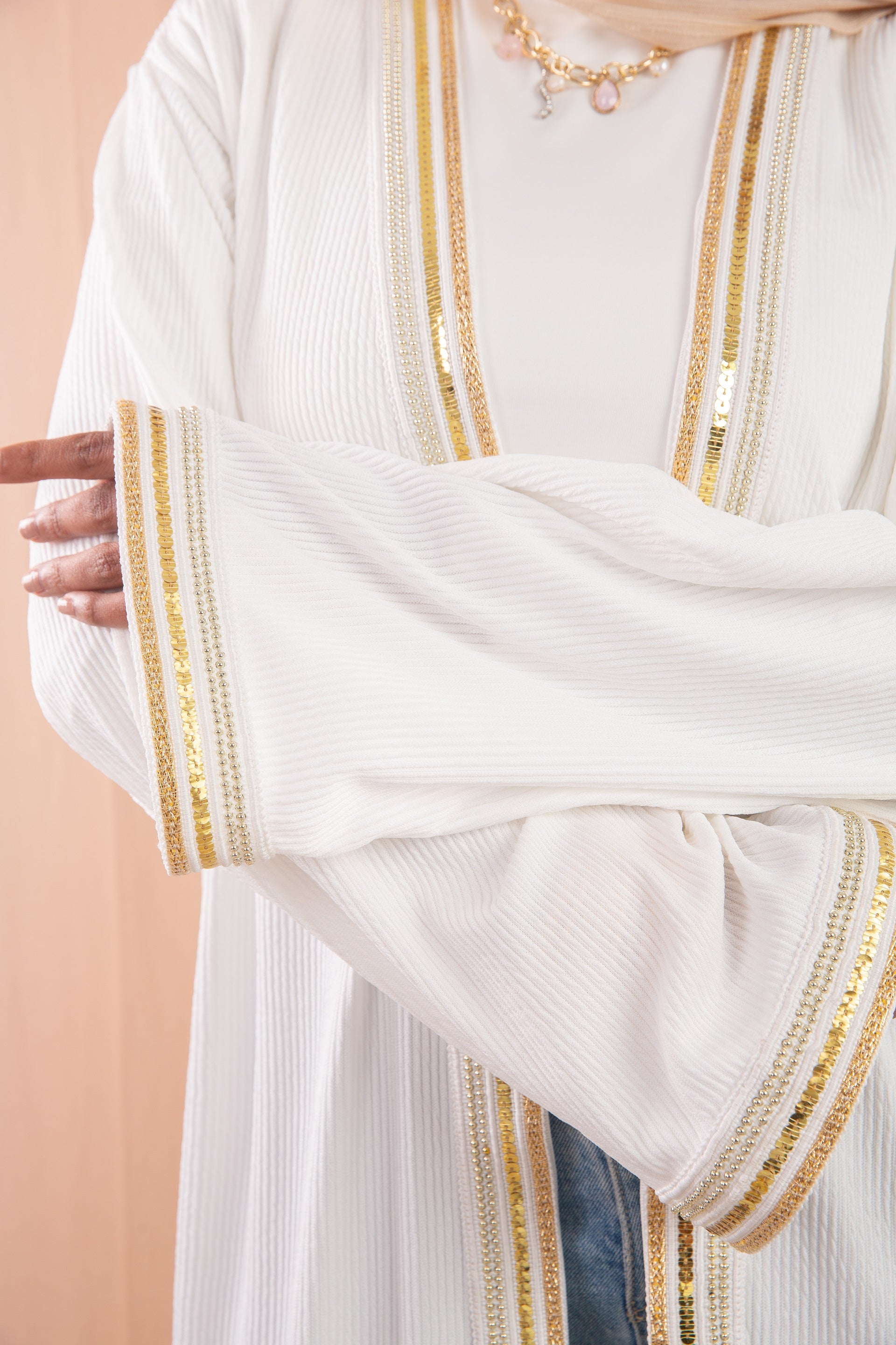 Nojom Kaftan  Off White crafted from crinkle rib-knitted fabric, is adorned with delicate gold lines, adding a touch of elegance and sophistication.