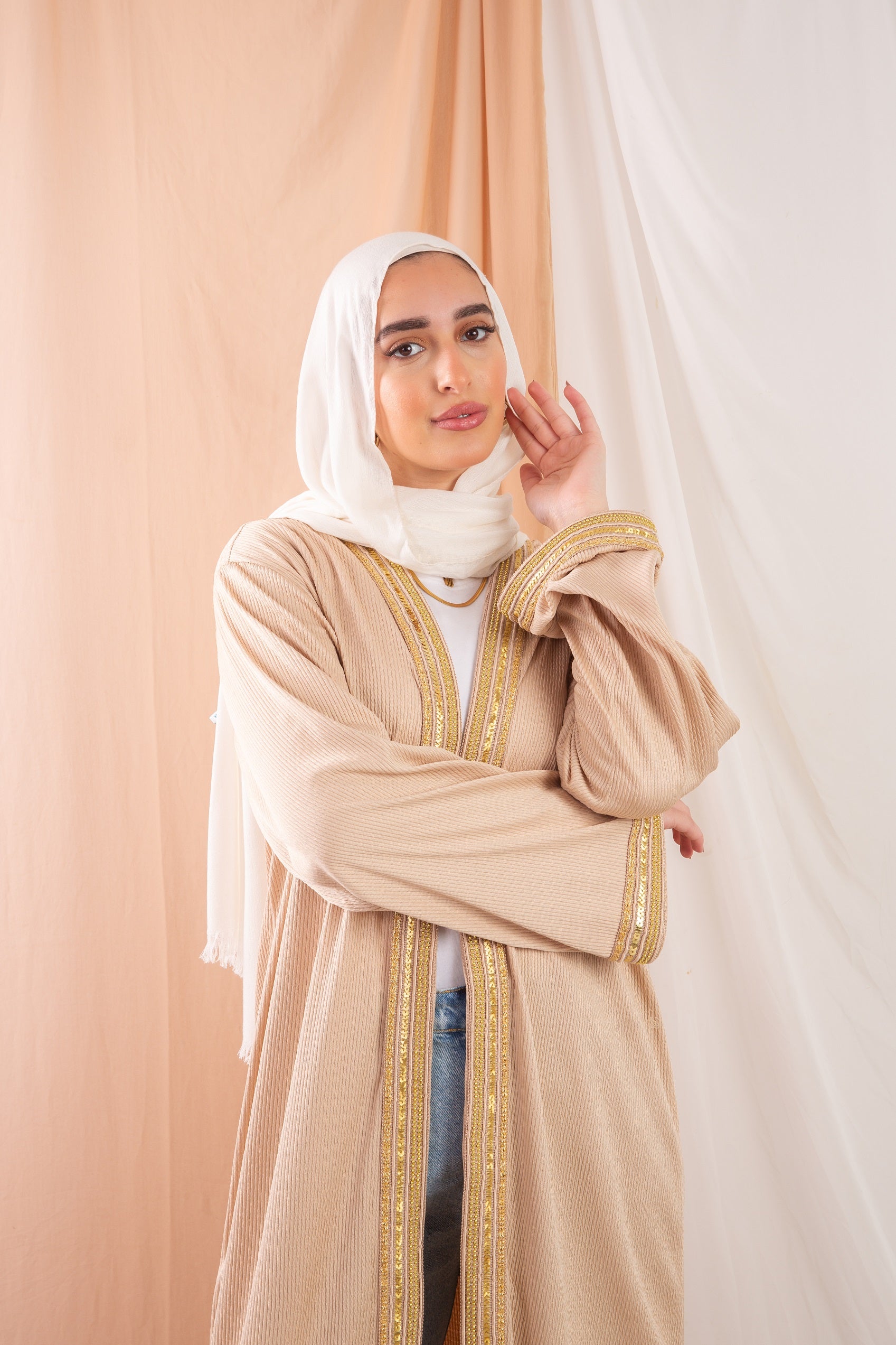 Nojom Kaftan beige crafted from crinkle rib-knitted fabric, is adorned with delicate gold lines, adding a touch of elegance and sophistication.