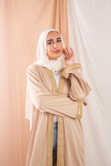 Nojom Kaftan beige crafted from crinkle rib-knitted fabric, is adorned with delicate gold lines, adding a touch of elegance and sophistication.