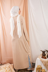 Nojom Kaftan beige crafted from crinkle rib-knitted fabric, is adorned with delicate gold lines, adding a touch of elegance and sophistication.