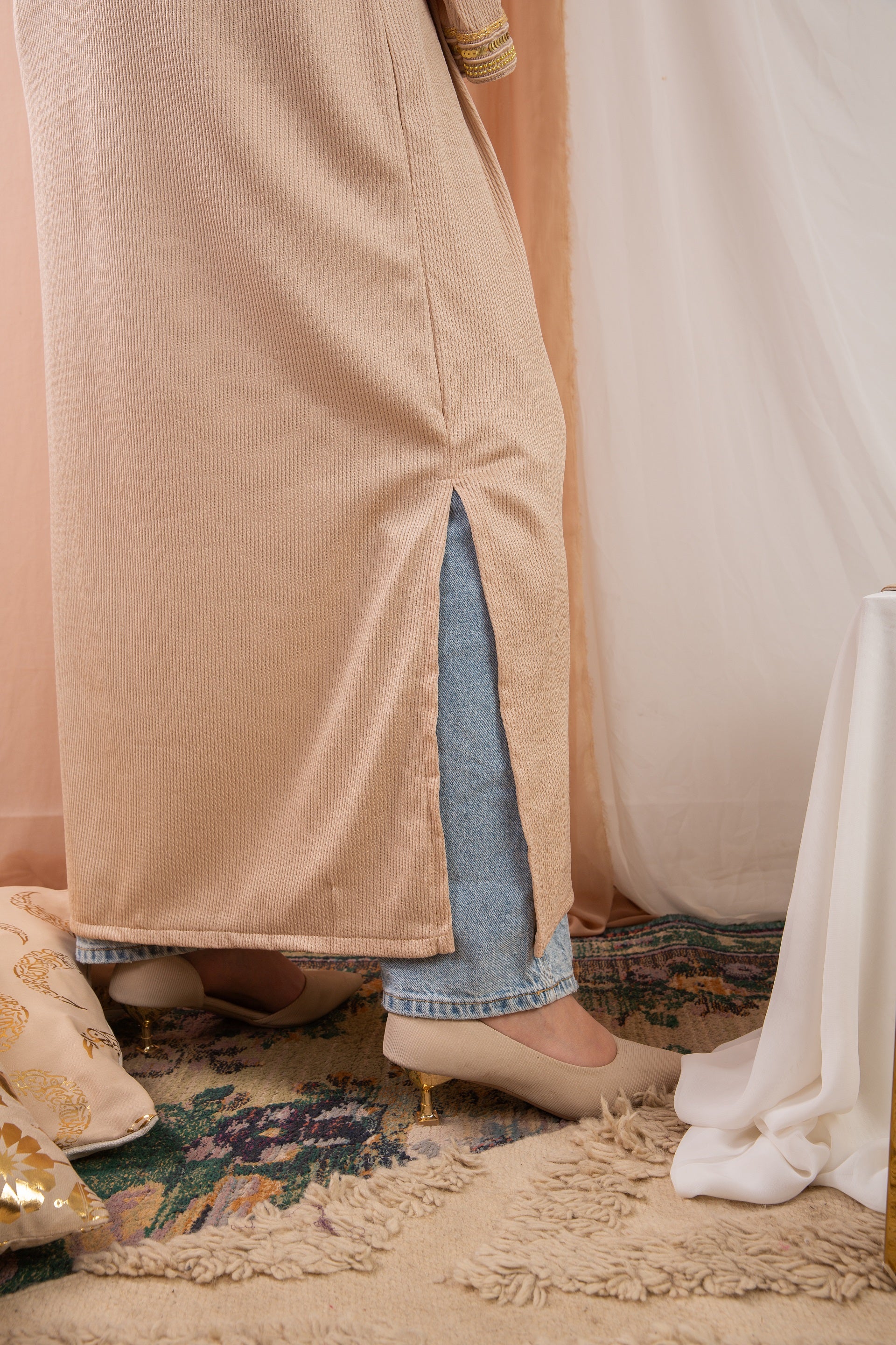 Nojom Kaftan beige crafted from crinkle rib-knitted fabric, is adorned with delicate gold lines, adding a touch of elegance and sophistication.