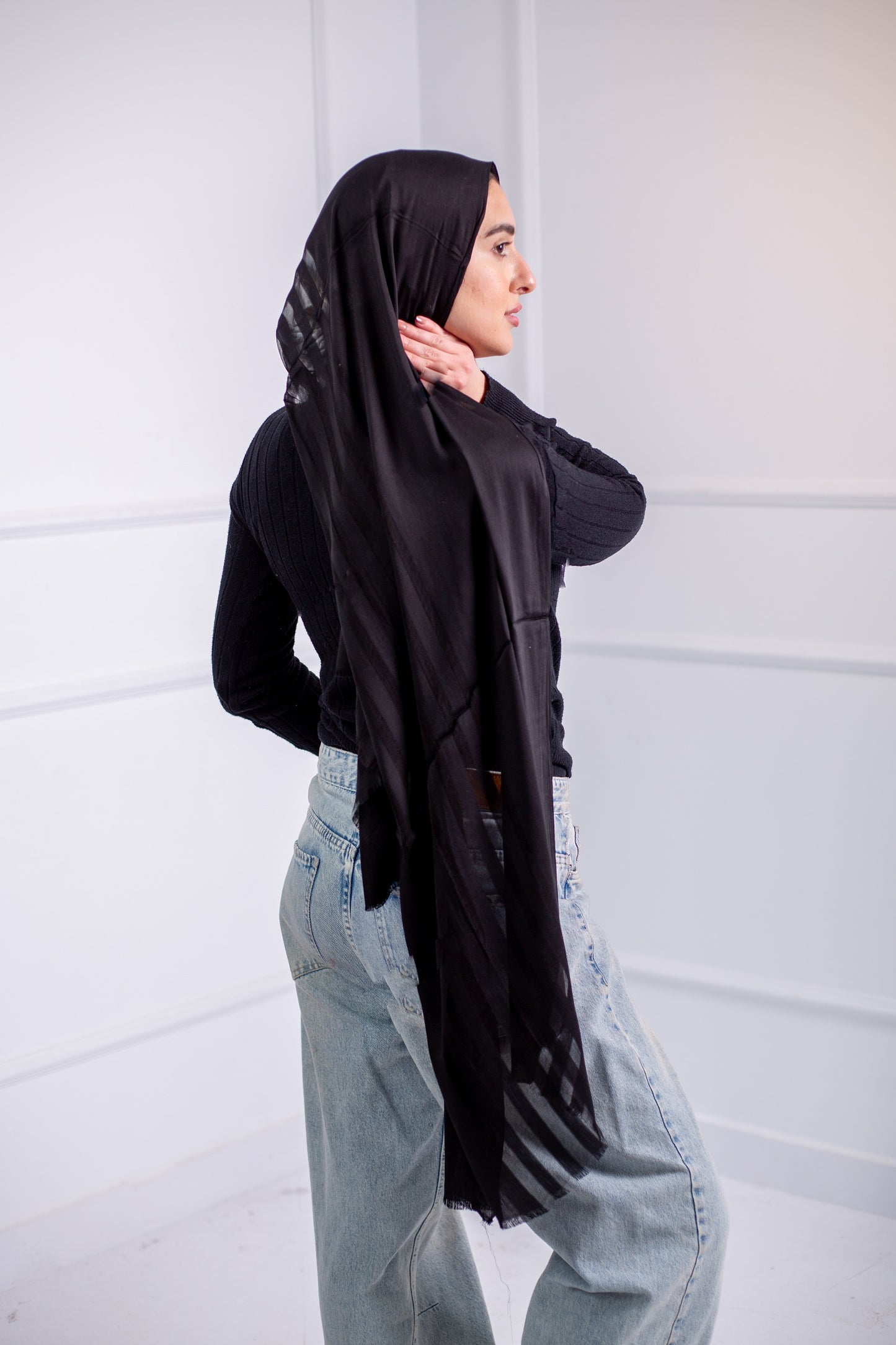 Silky black long hijab with line design, worn with casual jeans and a black top – back view 1